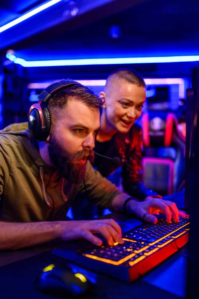 Focused gamer with headset playing game in neon lit cybercafe.