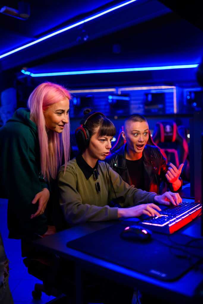 Gamer girl playing mmo game while her friends are cheering and h
