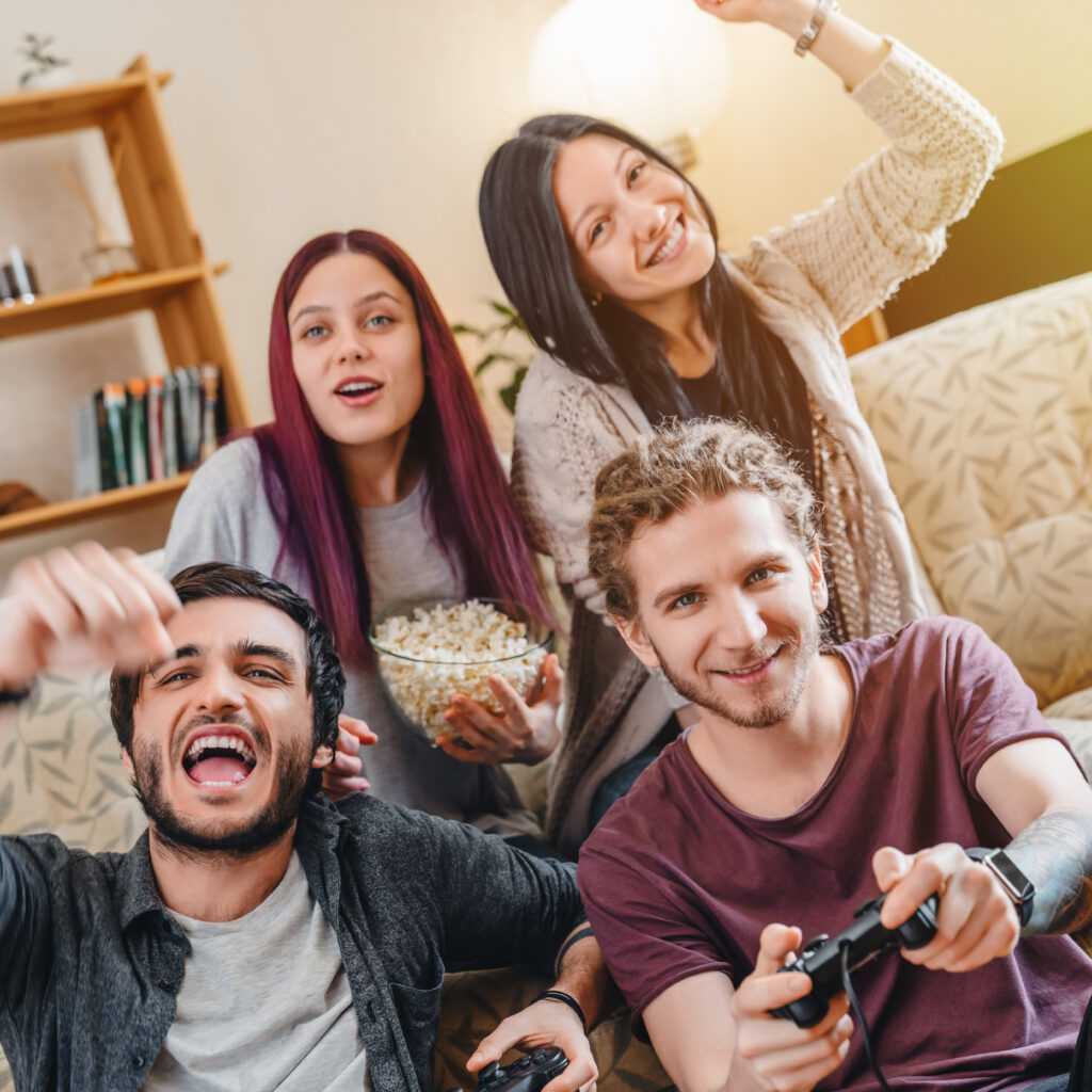 Group of young friends playing video games and celebrating together at home
