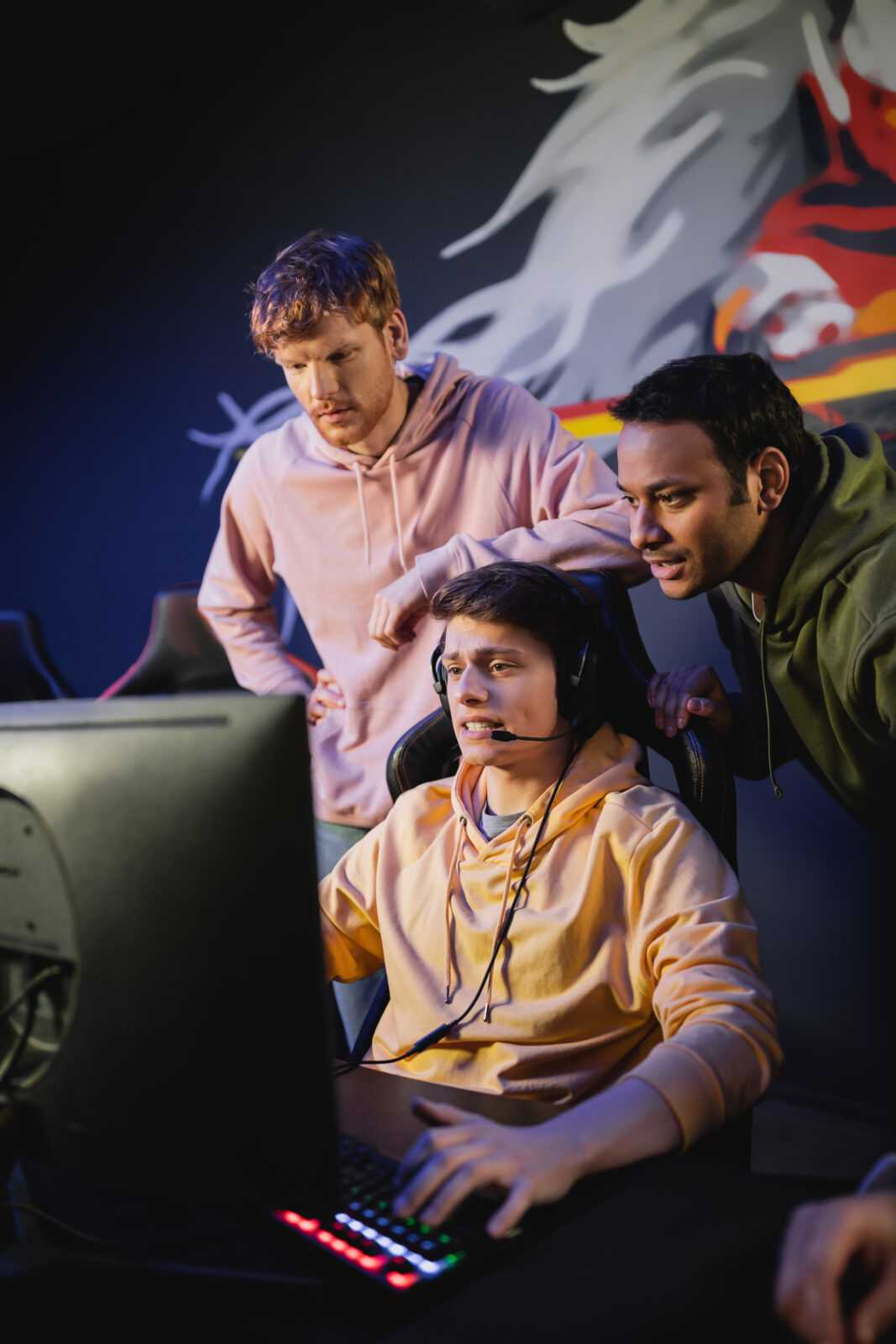 tensed man playing video game near interracial friends in cyber club